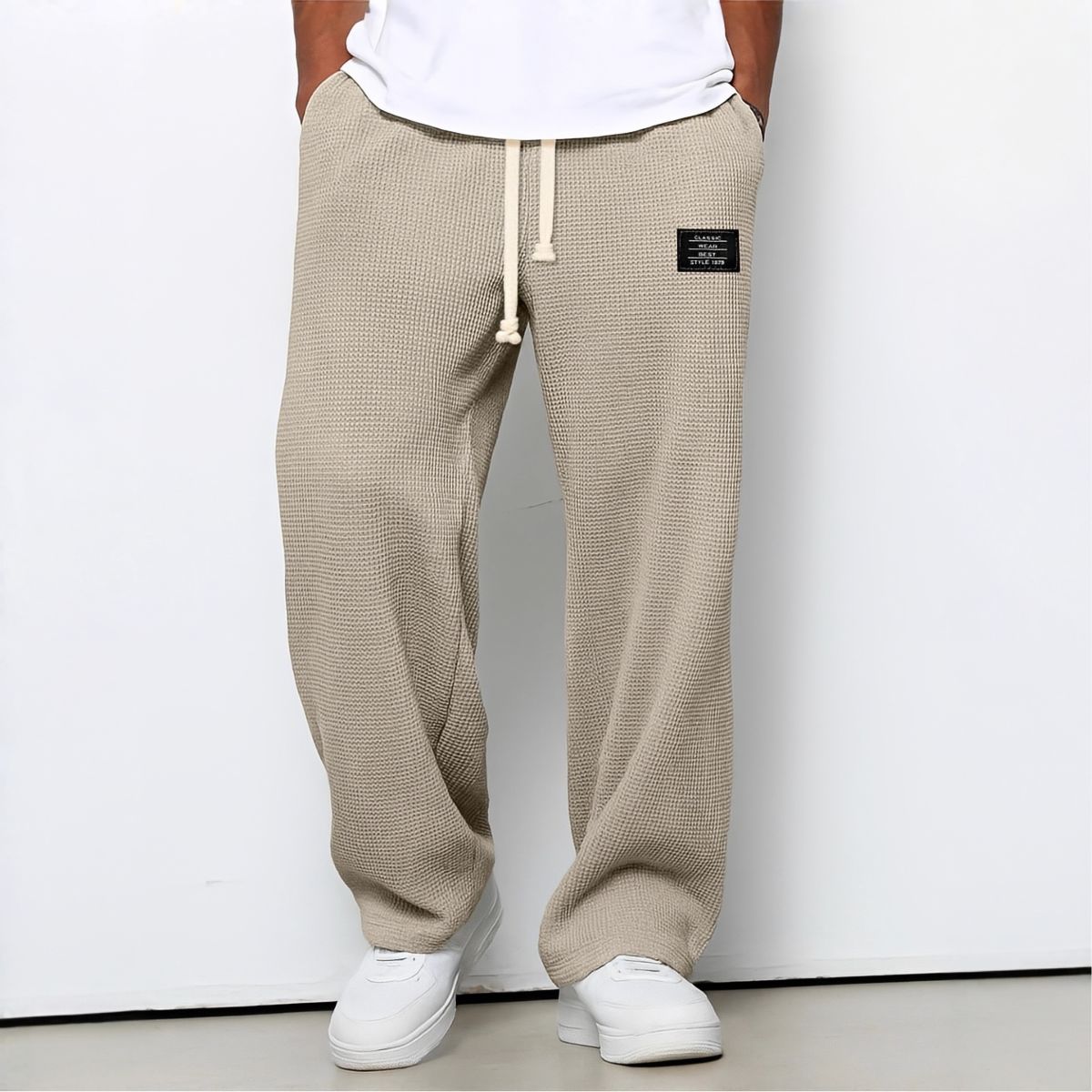 Frontansicht der Waffelstrick-Hose in Beige mit weißem Kordelzug, getragen mit weißem Shirt und Sneakern 7