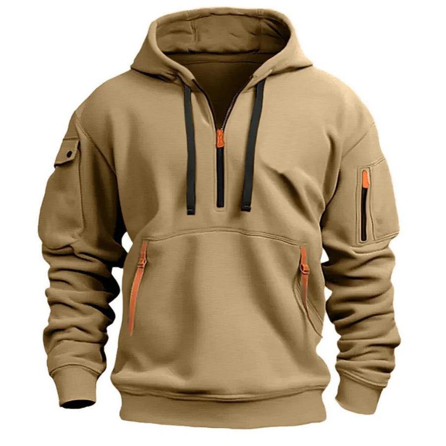 Sandbeiger Hoodie in Frontansicht mit schwarzen Kordeln, Ärmeltaschen und orangefarbenen Reißverschlusszügen 2