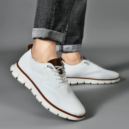 Weiße Herren-Sneaker aus Leder, sportlich, bequem, mit braunen Akzenten, auf grauem Hintergrund.