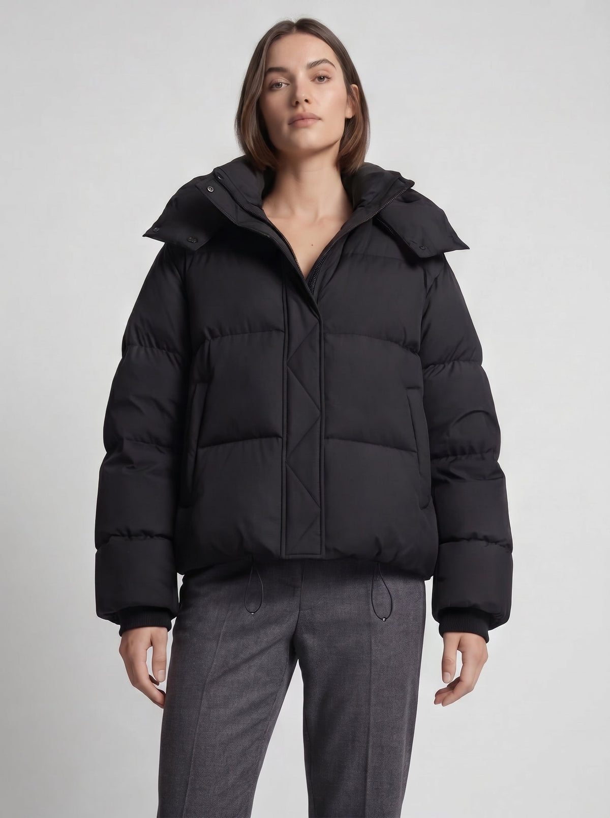 Model in der schwarzen Oversized-Steppjacke mit Stehkragen und Kordelzug, Halbkörper von vorn 6
