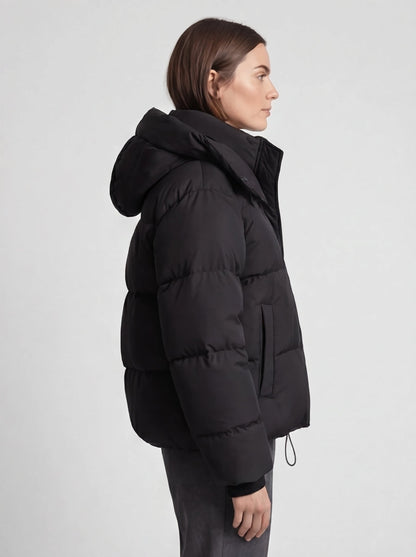 Seitenansicht der schwarzen Steppjacke am Model mit Kapuze, Eingrifftasche und Kordelzug am Saum 5