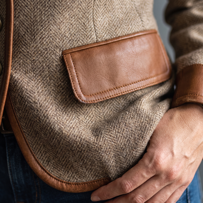 Detail der Taschenklappe aus Kunstleder mit Ziernaht, dazu Saumkante und Ärmelbündchen, eine Hand ruht an der Jacke. 5