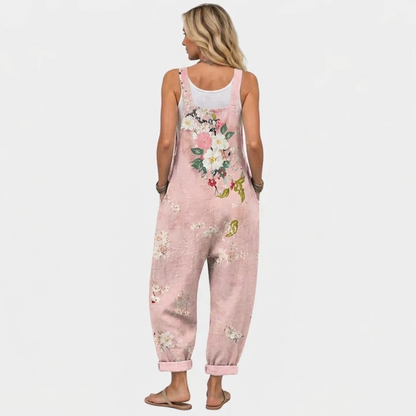 Rückansicht der Latzhose am Model mit breiten Trägern und dem Blumenmuster, das sich über den Rücken und die Beine zieht. 4