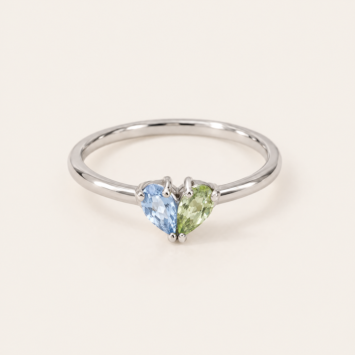 Silberfarbener Ring in Frontansicht, ein hellblauer und ein hellgrüner tropfenförmiger Stein bilden zusammen ein Herz. 5