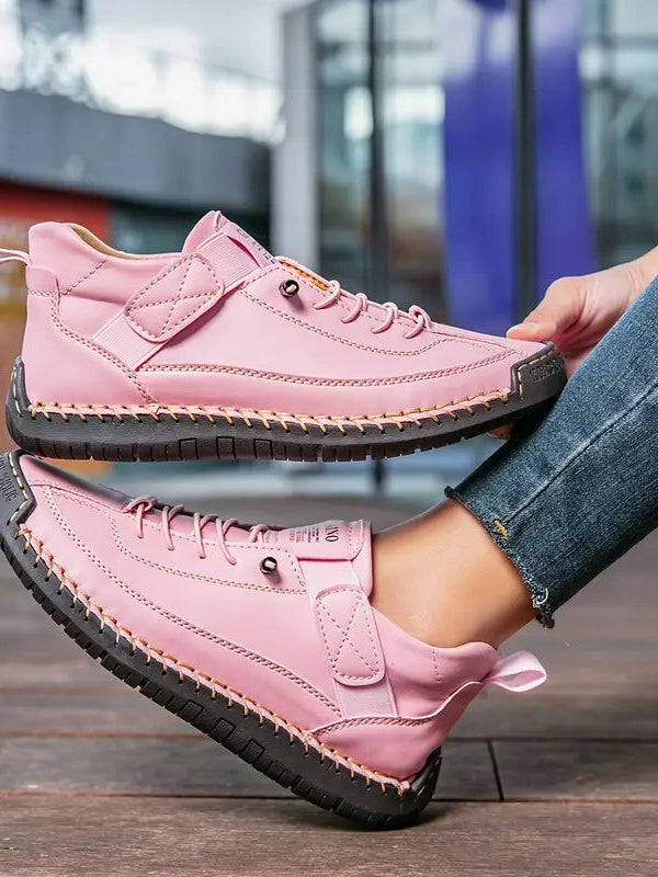 Rosafarbene Sneaker mit dunkler Sohle, getragen und seitlich auf Holzboden gehalten 13