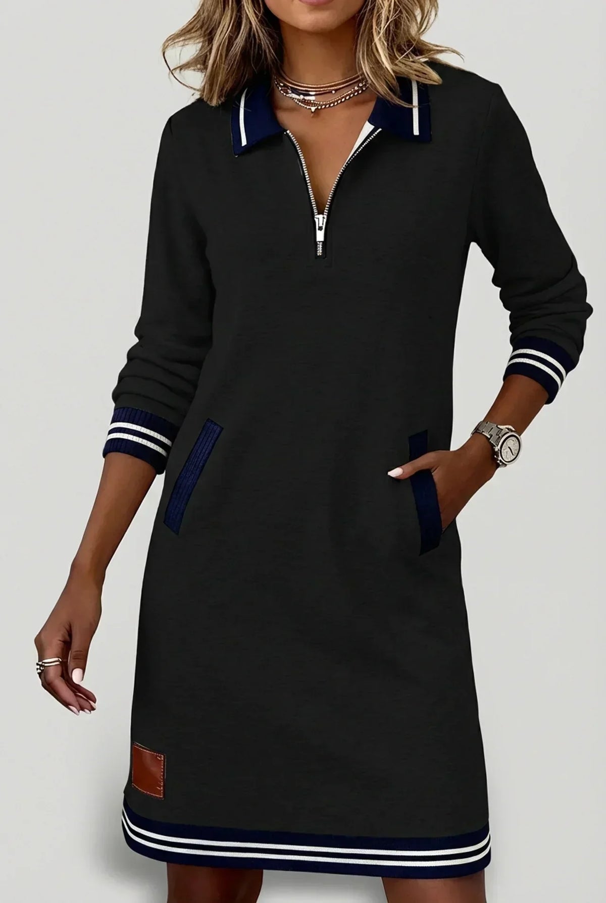 Schwarzes Kleid mit Streifenkragen und Reißverschluss vorn, marineblauen Besätzen an Taschen und Saum.