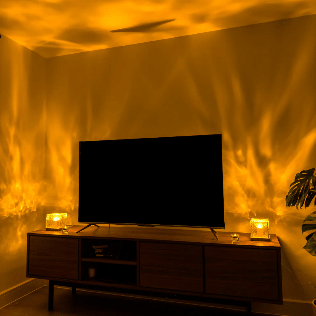 Wellenwürfel-LED-Tischlampe als Detail auf einem Holz-Sideboard neben dem Fernseher mit gelb-orangefarbenen Lichtwellen