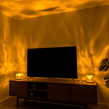 Wellenwürfel-LED-Tischlampe als Detail auf einem Holz-Sideboard neben dem Fernseher mit gelb-orangefarbenen Lichtwellen