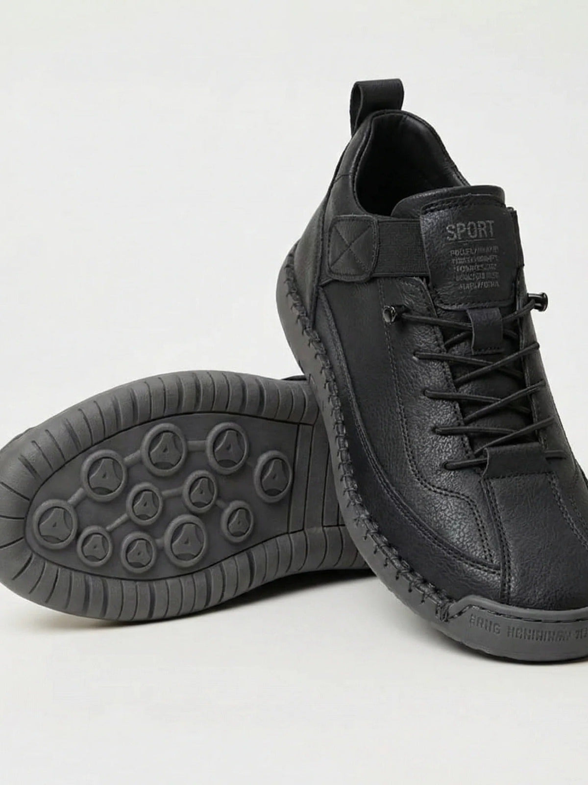 Schwarzer Sneaker mit grauer Sohle, ein Schuh aufgestellt, der andere zeigt das Sohlenprofil mit runden Noppen 1