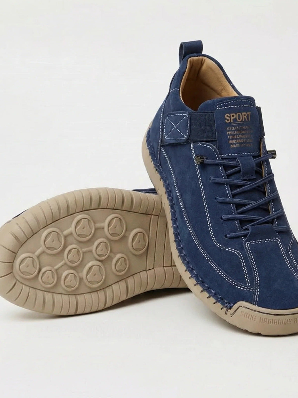 Marineblauer Wildleder-Sneaker mit heller Sohle, ein Schuh liegt mit sichtbarem Noppenprofil darunter 2