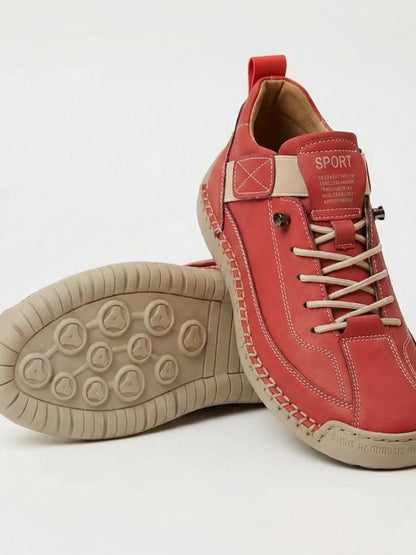 Roter Sneaker mit beiger Sohle und beigen Schnürsenkeln, ein Schuh gekippt über dem anderen 10