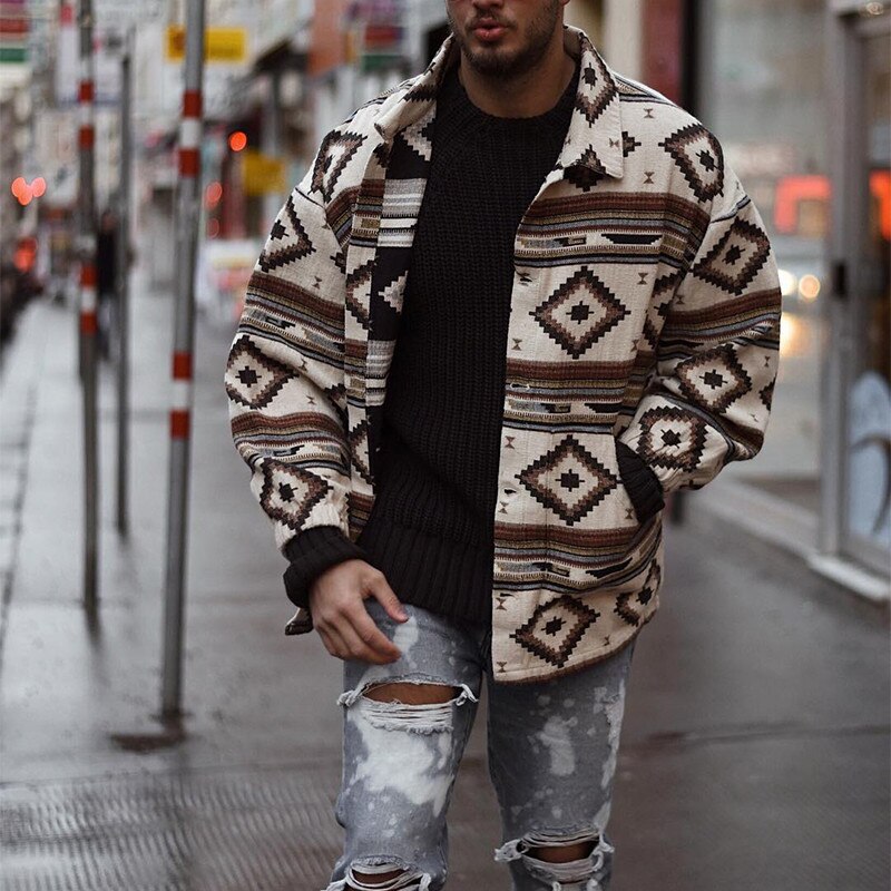 Mann in gemusterter Jacke und zerrissener Jeans auf Stadtstraße, modischer Streetwear-Look.