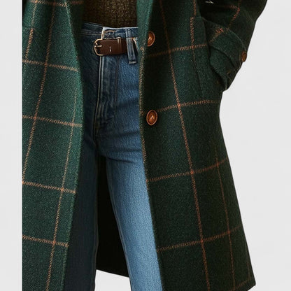 Detailaufnahme der Taillenpartie mit zwei braunen Knöpfen und Klappentasche, Hand in der Tasche, darunter Jeans mit Ledergürtel. 5