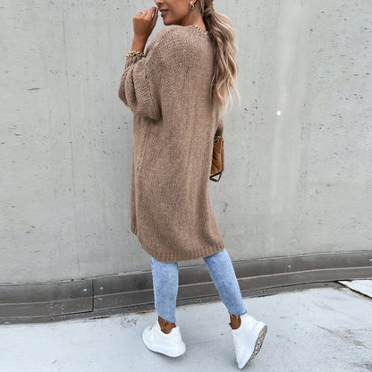 Frau in khaki Strickjacke, blaue Jeans, weiße Sneaker, lässiger Herbstlook, Straßenmode.