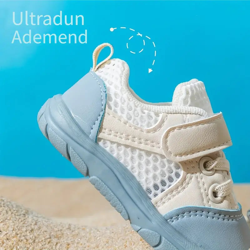 Beiger und blauer Kinderschuh, atmungsaktiv, mit Klettverschluss, auf Sandhintergrund.