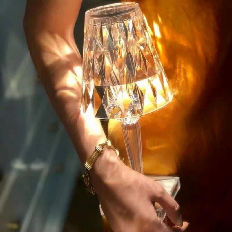 Person hält Kristalltischlampe, goldene Kleidung, elegantes Design, stilvolle Beleuchtung.