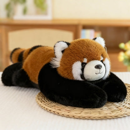 Roter-Panda-Plüschtier mit rotbraunem Fell, schwarzen Armen und geringeltem Schwanz auf einer Bastmatte