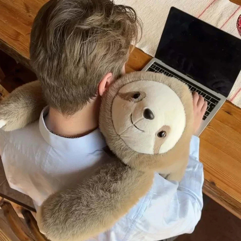 Draufsicht auf einen Mann am Laptop mit Faultier-Plüschtier um den Nacken
