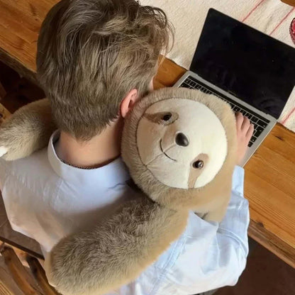 Draufsicht auf einen Mann am Laptop mit Faultier-Plüschtier um den Nacken