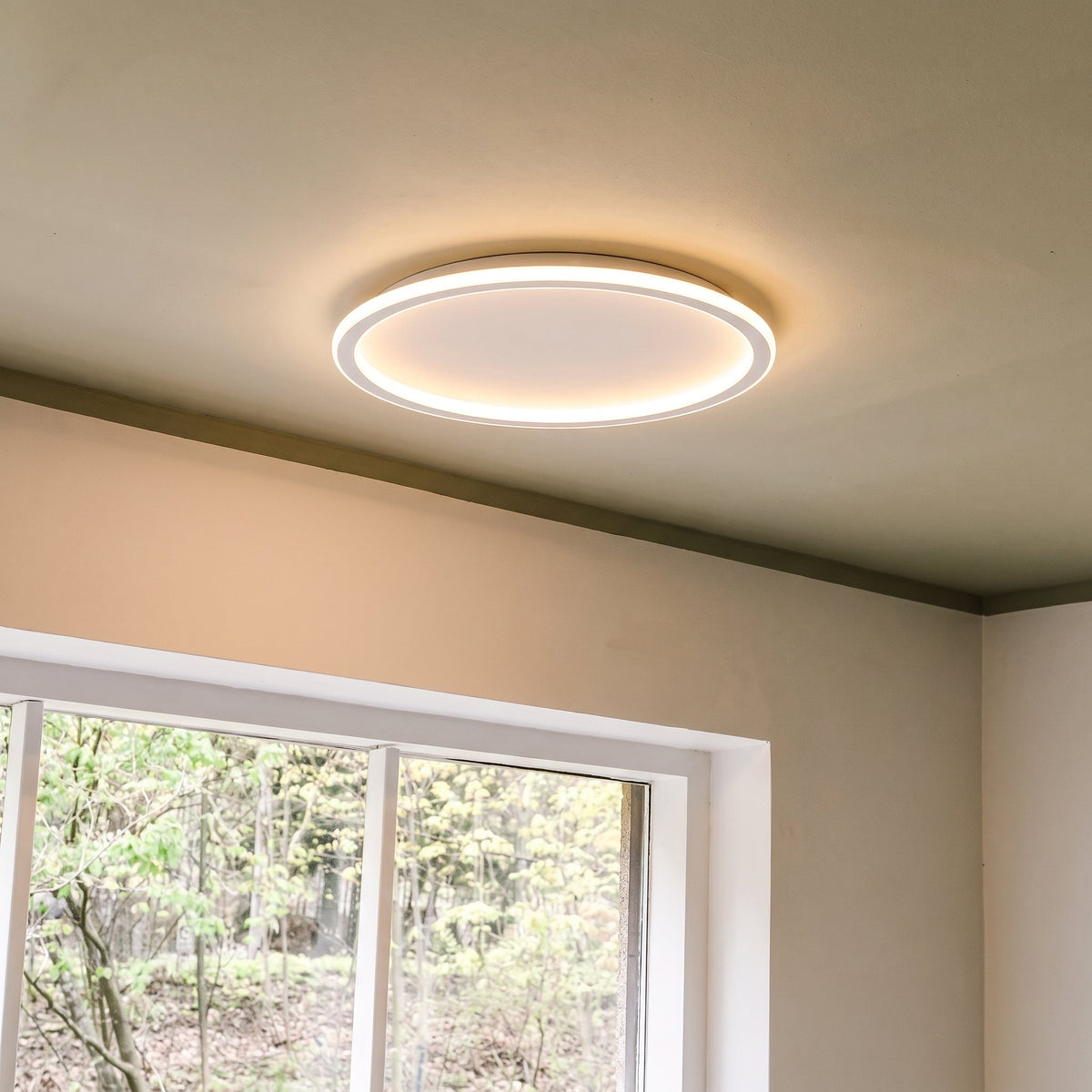 Weiße flache LED-Deckenleuchte, weitere Ansicht neben einem Fenster.