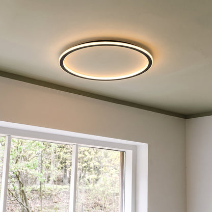 Schwarze runde LED-Deckenleuchte neben einem Sprossenfenster, weitere Ansicht.