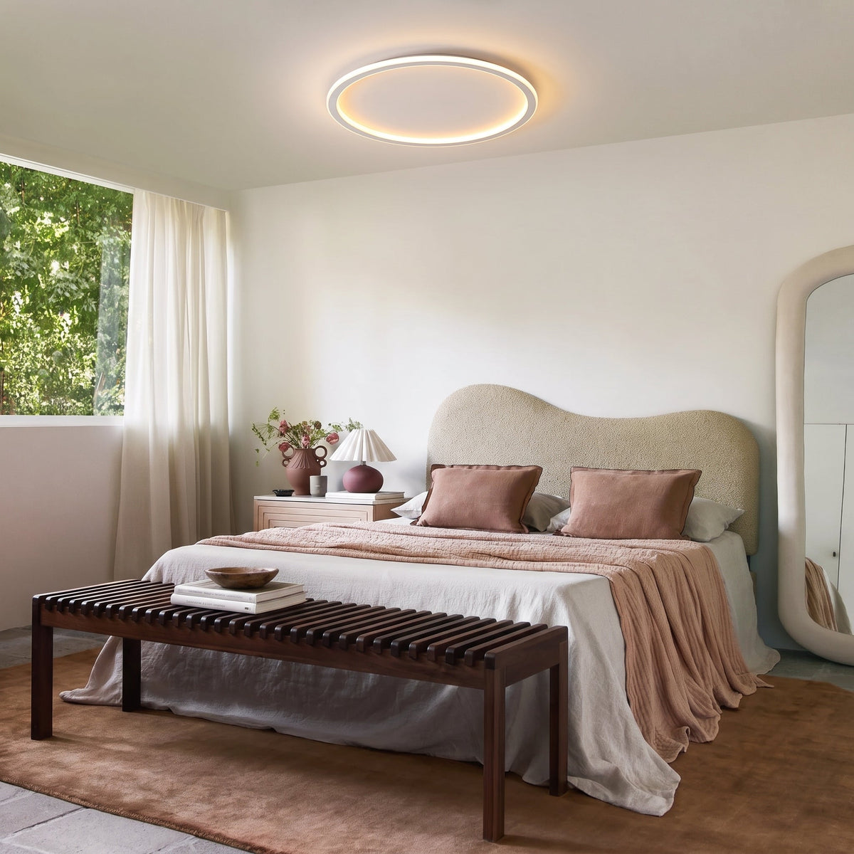 Weiße runde LED-Deckenleuchte über einem hellen Schlafzimmer.