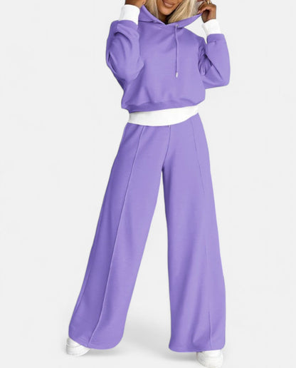 Frau in lila Jogginganzug, Kapuzenpullover und weite Hose, sportlich, modisch, bequem.
