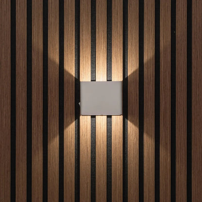Frontansicht der hellgrauen Wandleuchte an Holzlamellenwand mit warmem Lichtkegel nach oben und unten 6