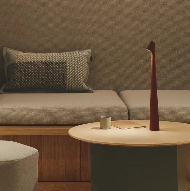 Wiederaufladbare LED-Tischlampe, weitere Ansicht auf einem runden Holztisch mit Heft.