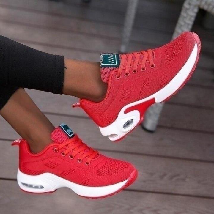 Rote Sneaker aus Mesh mit weißer Sohle, getragen zu schwarzer Leggings.