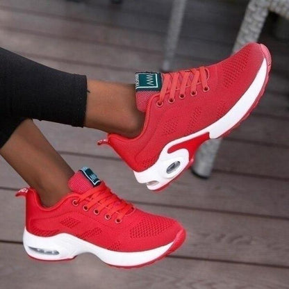 Rote Sneaker aus Mesh mit weißer Sohle, getragen zu schwarzer Leggings.
