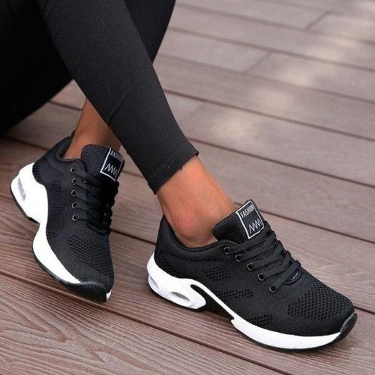 Schwarze Strick-Sneaker mit weißer Sohle und Luftpolster, getragen zu schwarzer Leggings.