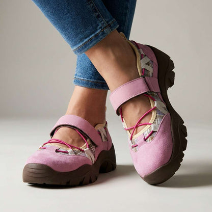 Rosafarbene Wildlederslipper mit Klettriemen, pinkem Gummizug und Karoeinsatz, im Studio zu Jeans getragen.