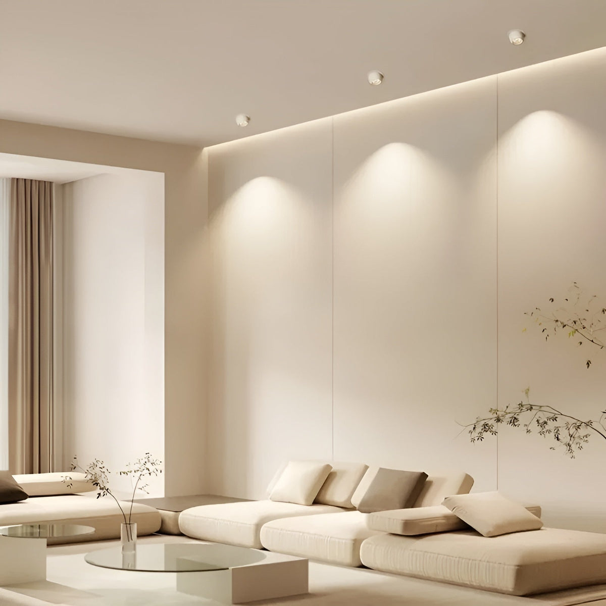 Drei weiße Deckenstrahler beleuchten eine helle Wand über einem cremefarbenen Sofa im Wohnzimmer 2