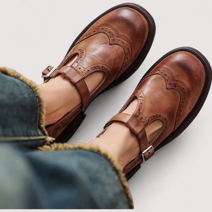 Braune Leder-Mary-Jane-Ballerinas mit Lochmuster und Schnallenriemen, von oben getragen.