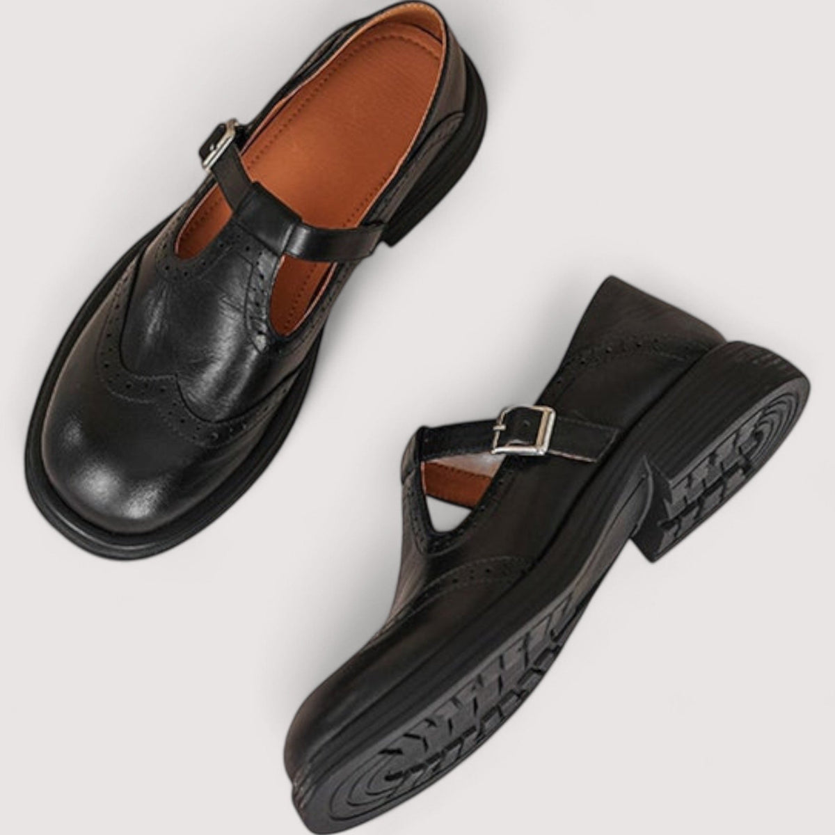Schwarze Mary-Jane-Ballerinas von oben mit orangefarbenem Innenfutter und profilierter Gummisohle.