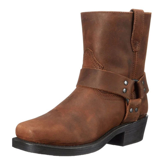 Brauner Lederstiefel in Schrägansicht von vorne mit Riemen, Nietenschnalle, eckiger Spitze und flachem Blockabsatz. 1