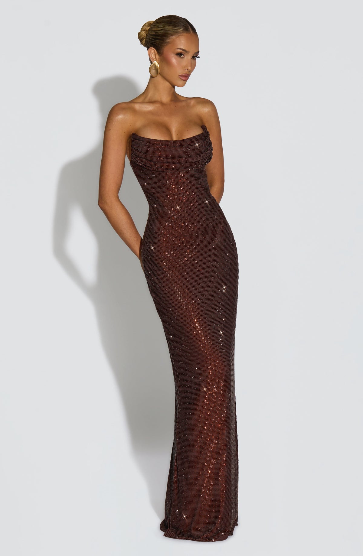 Braunes Maxikleid mit Strasssteinen schräg von vorne, Hände am Rücken, figurbetonte Silhouette bis zum Boden. 12