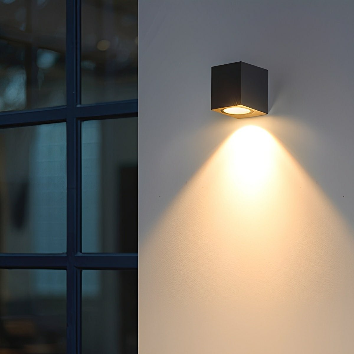 Schwarze Würfelleuchte neben dunklem Sprossenfenster, warmer Lichtkegel fällt an die Wand 11