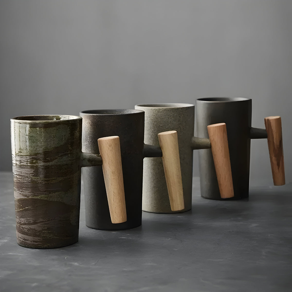 Vier Becher mit Holzgriff nebeneinander gereiht, grün-braun glasiert, schwarz, sandfarben und grau 5