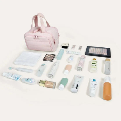 Rosa Kulturbeutel mit ausgebreitetem Inhalt wie Kosmetik, Pflegeflaschen, Handtuch, Make-up-Palette und Zahnbürste, another view