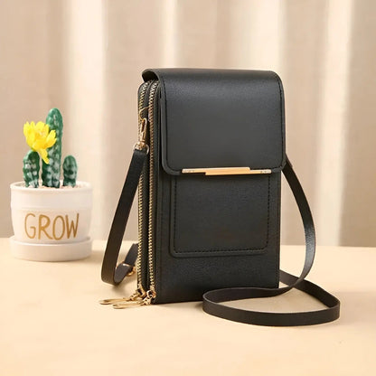 Schwarze Lederhandtasche mit Schulterriemen, goldenen Reißverschlüssen, neben Kaktus im Topf.