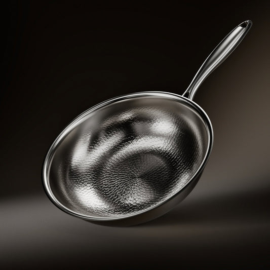 Wokpfanne aus Titan mit gehämmerter Innenfläche und langem Metallgriff, schräg von oben vor dunklem Hintergrund