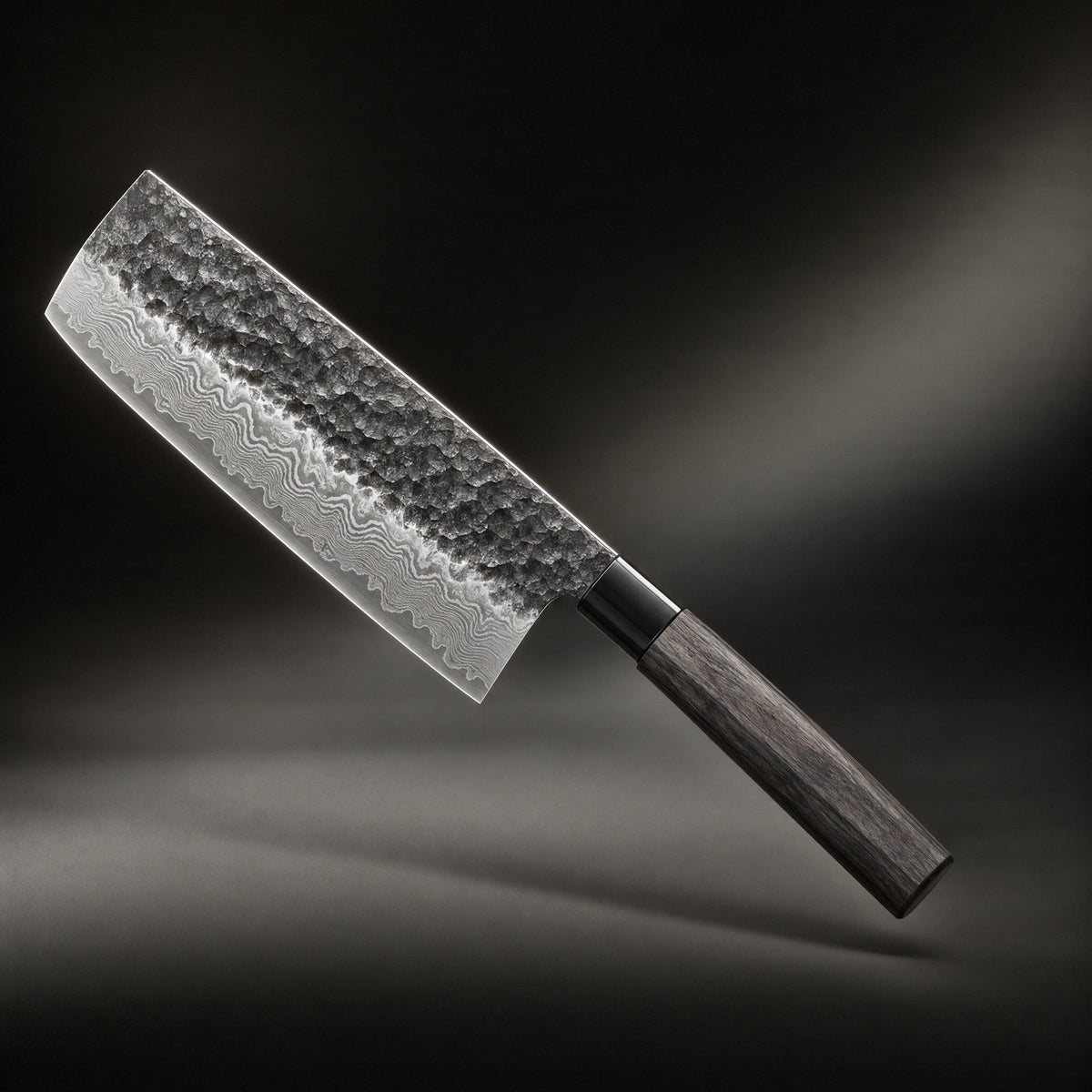 Messer mit breiter, gehämmerter Klinge und gemasertem Schichtstahl an der Schneide, schräg vor dunklem Hintergrund schwebend, dunkler Holzgriff mit schwarzer Zw 1