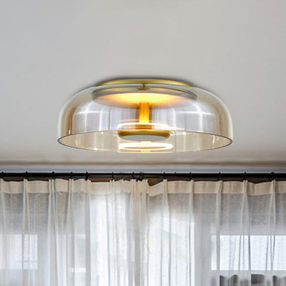 Flache Deckenleuchte mit bernsteinfarbenem Glasschirm und goldenem Rahmen vor einem Fenster mit hellem Vorhang 2