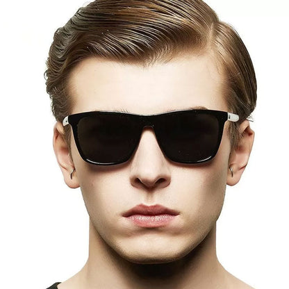 Junger Mann mit zurückgekämmtem Haar trägt die Sonnenbrille mit dunklen Gläsern in der Frontansicht 2