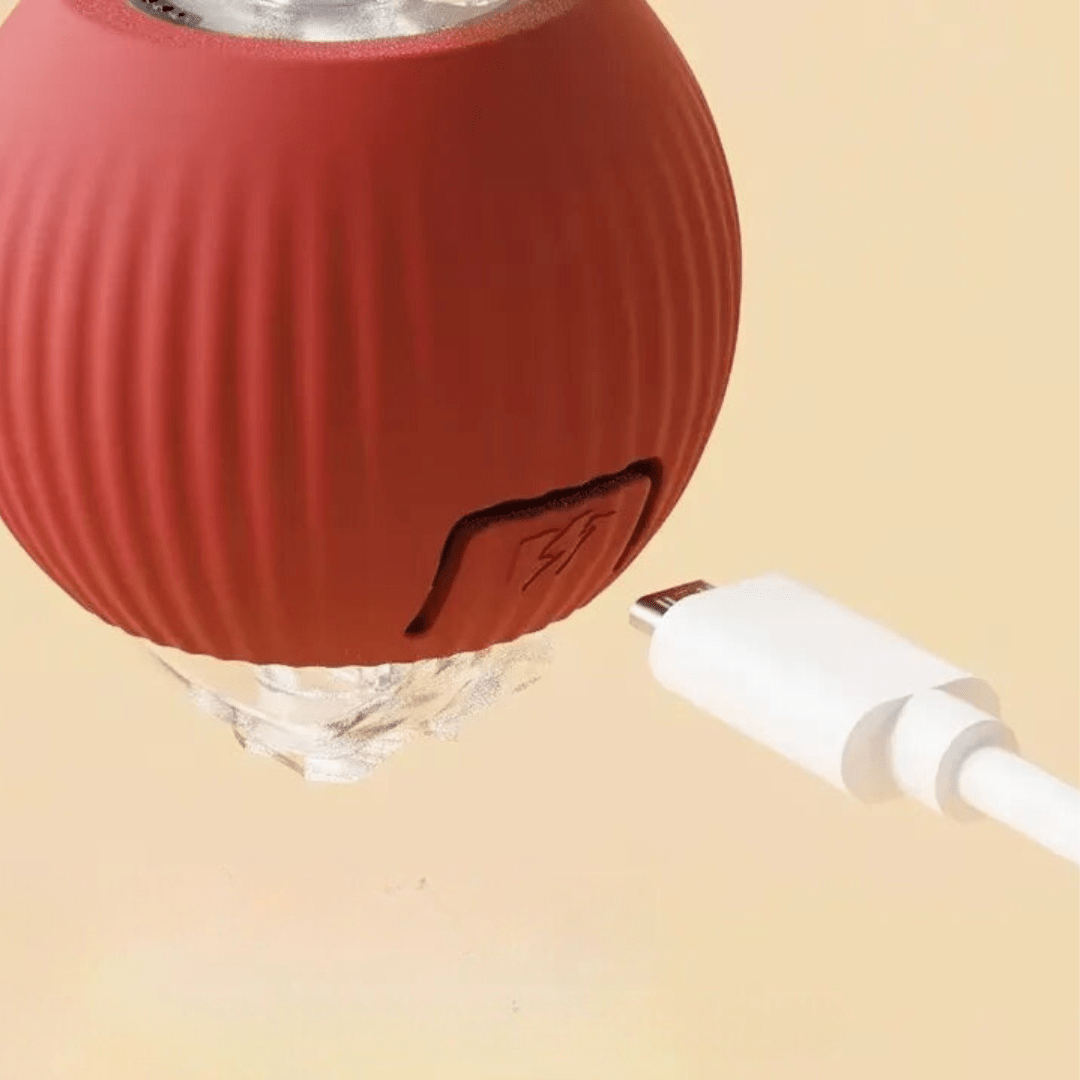 Nahaufnahme des roten gerippten Balls mit Ladeöffnung und weißem USB-Kabel.