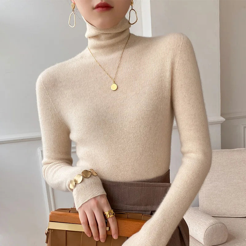 Beigefarbener, fein gerippter Rollkragenpullover an einem Model, kombiniert mit braunem Rock, goldener Kette und Armband 1