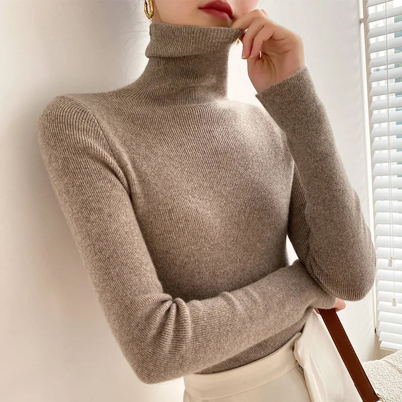 Graubrauner Rollkragenpullover am Model, Hand am hochgezogenen Kragen, kombiniert mit heller Hose 6