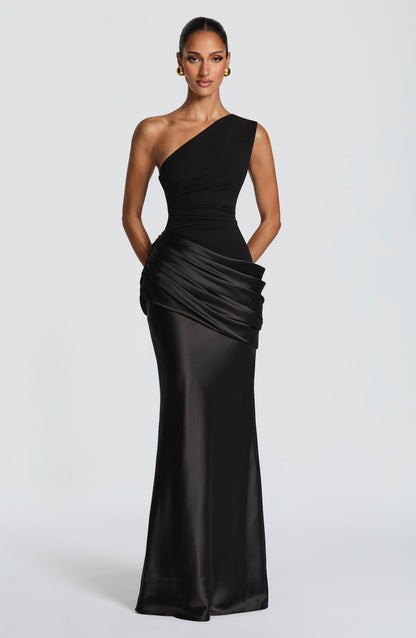 Schwarzes Maxikleid mit einer Schulter, gerafftem Satin an der Hüfte und goldenen Ohrringen in der Frontalansicht. 20